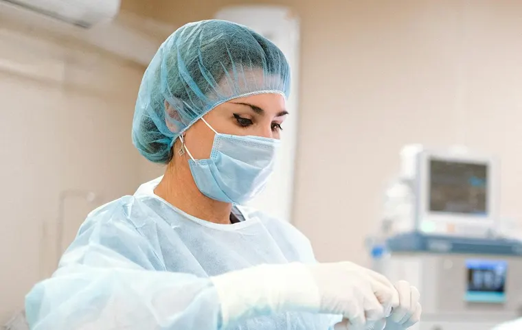 Médica con mascarilla y gorro preparando material en un quirófano