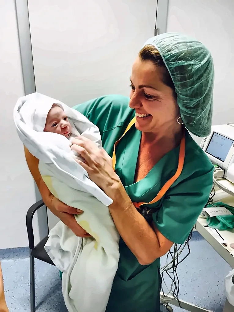 La Dra. Baixauli sonriendo con un recién nacido en brazos